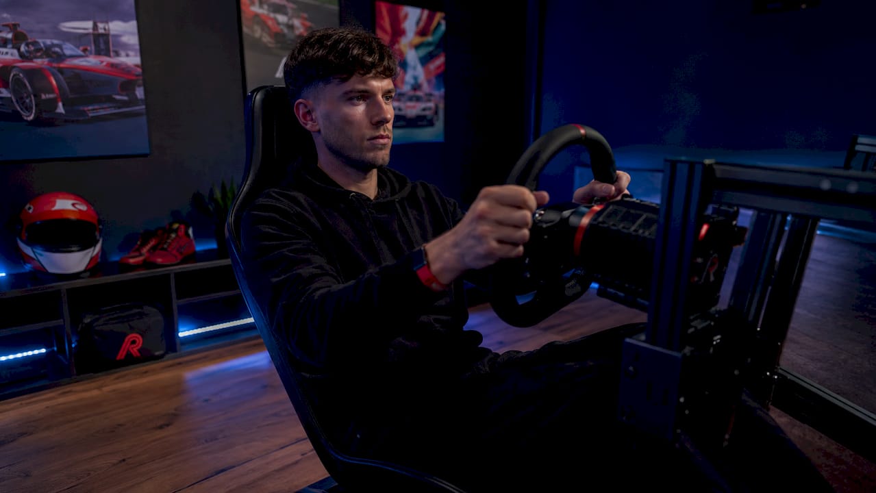 Man geniet van een racesimulatie thuis met een professioneel stuur en pedalen.