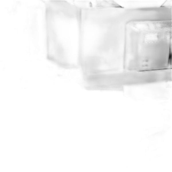 Een wazige, overbelichte afbeelding toont een transparante rechthoekige container-Fanatec's GT Cockpit Triple Monitor Expansion Kit (wit)-met een ander object gedeeltelijk zichtbaar op de achtergrond.